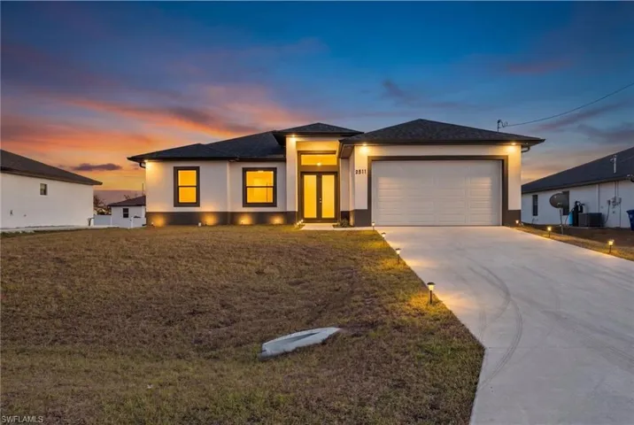 Prairie-style home with a garage, concrete driveway, a front lawn, and stucco siding