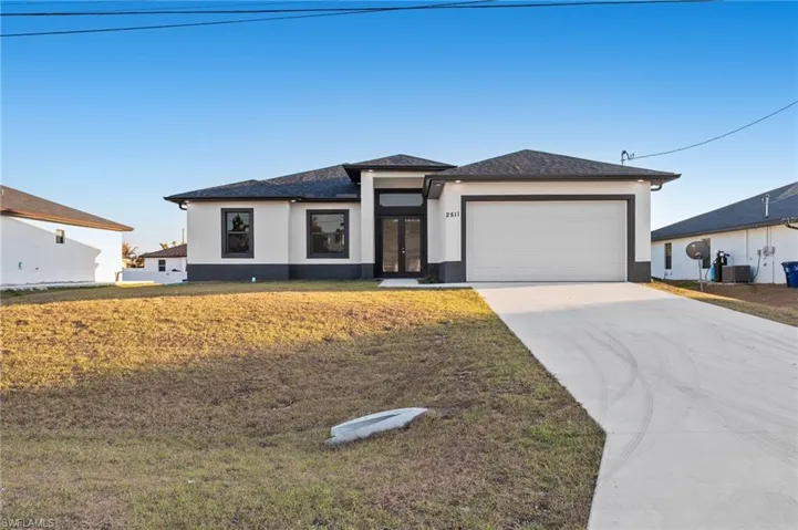 Prairie-style house with a front yard, stucco siding, french doors, concrete driveway, and a garage