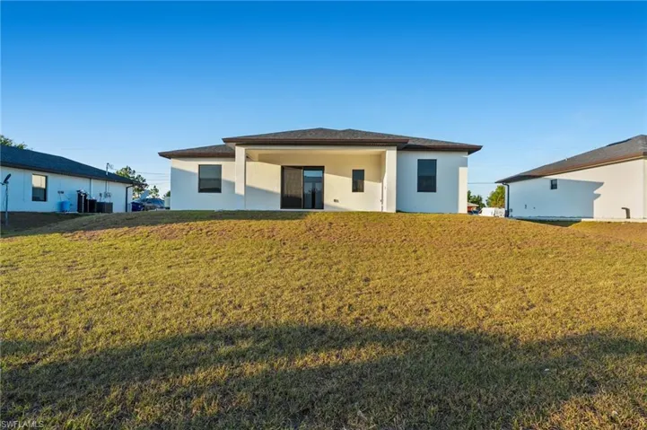 View of front of house with stucco siding, a front lawn, and a patio
