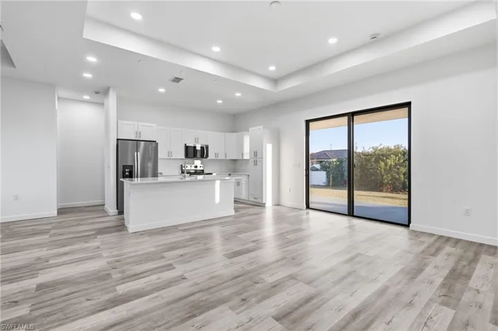 Kitchen with a center island, open floor plan, white cabinetry, stainless steel appliances, and a tray ceiling
