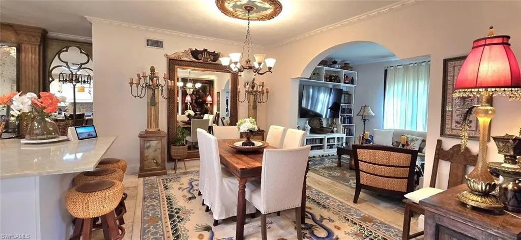 Dining area featuring ornamental molding, arched walkways, and a chandelier