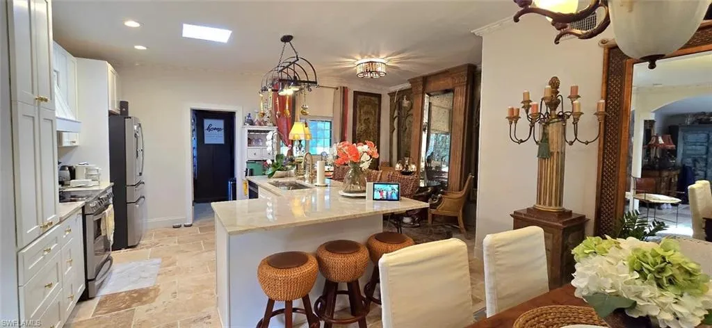 Kitchen with stainless steel appliances, white cabinetry, a kitchen breakfast bar, light stone finish flooring, and arched walkways