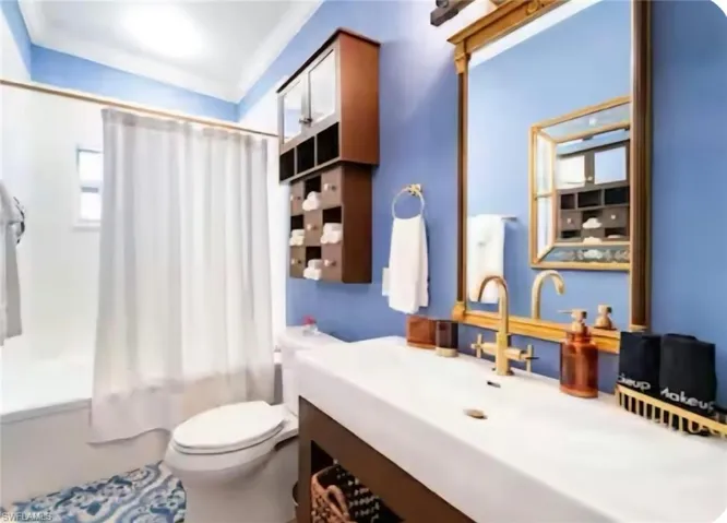 Bathroom featuring toilet, shower / bath combo with shower curtain, and vanity