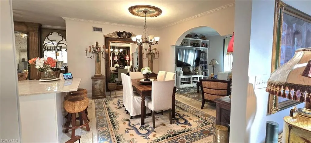 Dining room with arched walkways, a chandelier, and ornamental molding