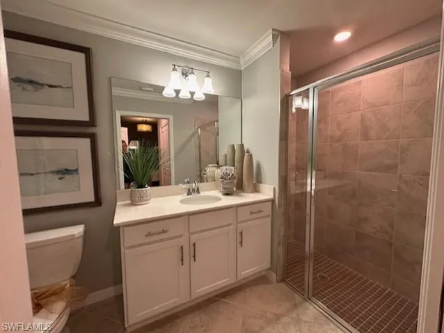 Bathroom featuring toilet, tile patterned flooring, crown molding, and vanity