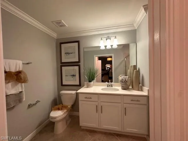 Bathroom with vanity, toilet, a shower with shower door, and crown molding
