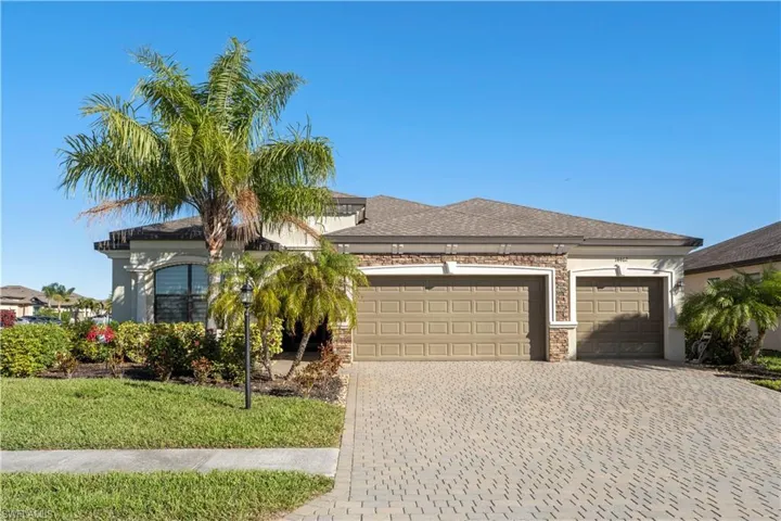 View of front facade featuring a garage, decorative driveway, a front yard, stone siding, and a shingled roof