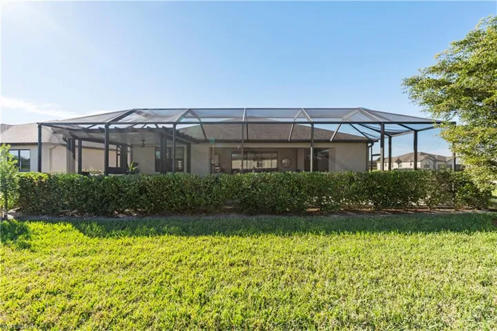 Rear view of house with a lanai, a sunroom, and a yard