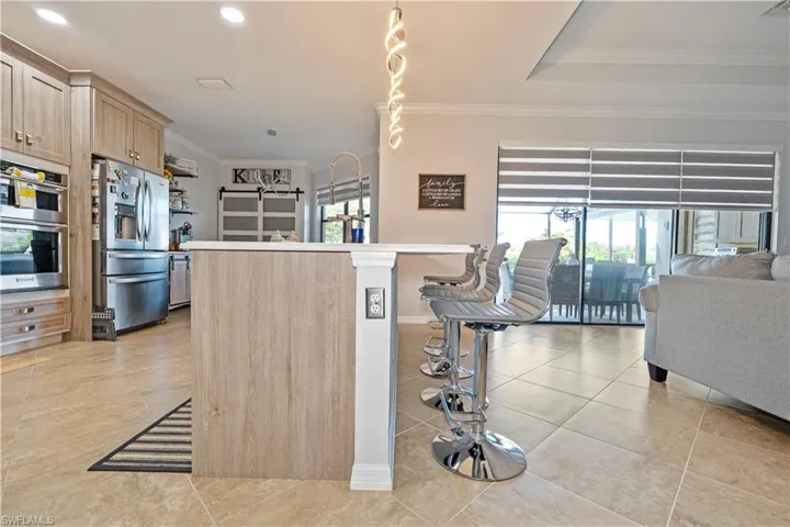 Kitchen featuring appliances with stainless steel finishes, light brown cabinets, ornamental molding, light countertops, and light tile patterned floors