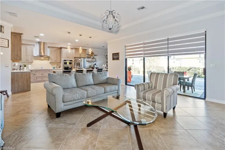Living area featuring a chandelier, ornamental molding, recessed lighting, and light tile patterned flooring