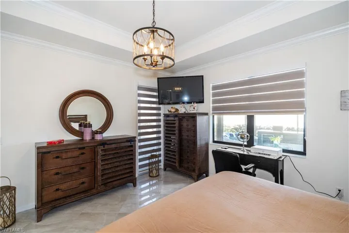 Bedroom featuring a tray ceiling, ornamental molding, and a chandelier