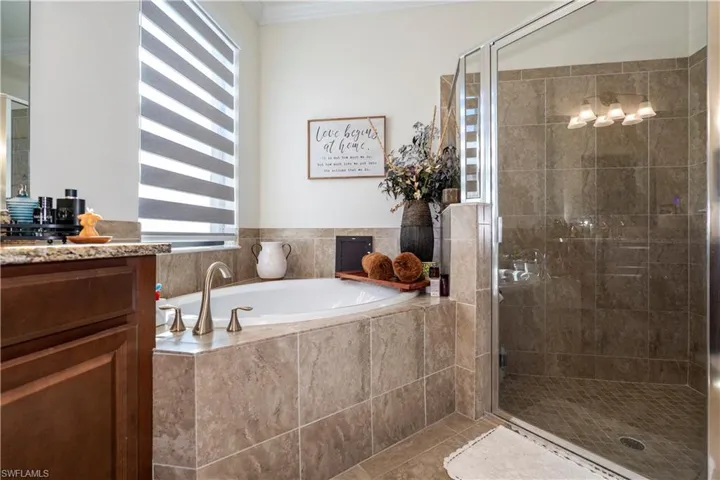 Bathroom featuring vanity, a stall shower, a garden tub, crown molding, and tile patterned floors