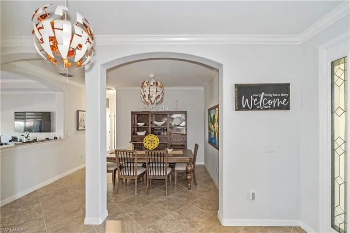 Dining area featuring crown molding, arched walkways, and a chandelier
