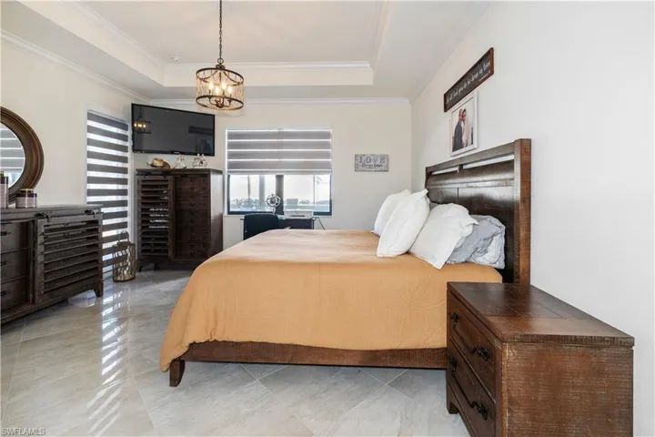 Bedroom featuring crown molding, a tray ceiling, and a chandelier