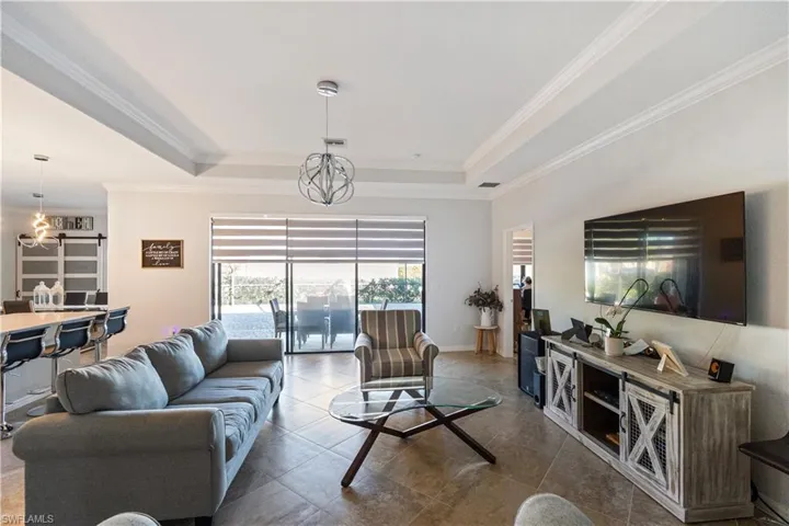 Living room featuring a chandelier, a tray ceiling, and crown molding