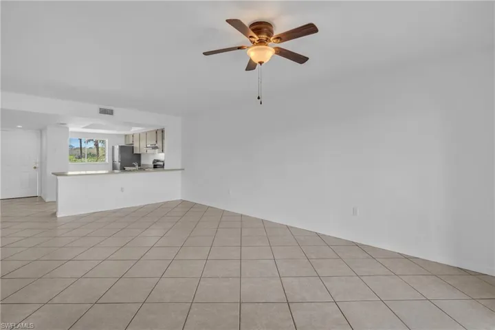 Unfurnished living room with ceiling fan and light tile patterned flooring