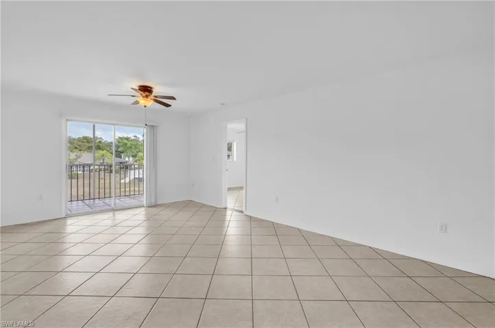 Empty room with ceiling fan and light tile patterned flooring