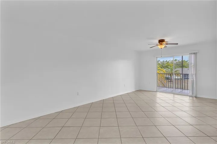 Empty room with a ceiling fan and light tile patterned floors