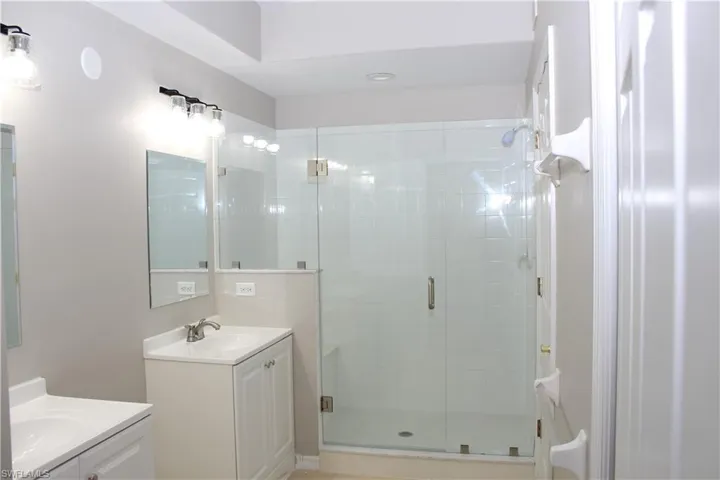 Bathroom featuring a shower with shower door and double vanity