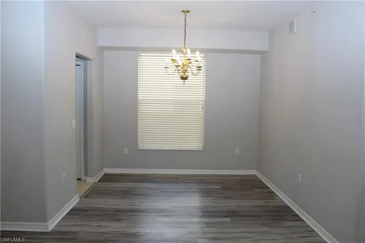 Unfurnished room featuring dark wood-type flooring and a notable chandelier