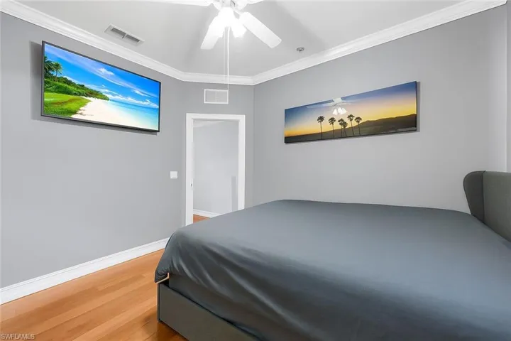 Bedroom featuring light wood-type flooring, crown molding, and ceiling fan