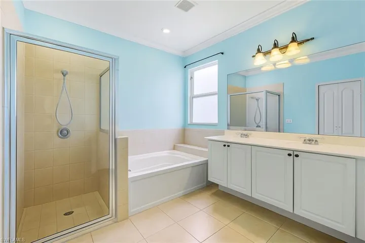Bathroom with double vanity, ornamental molding, light tile patterned floors, a shower stall, and a bath
