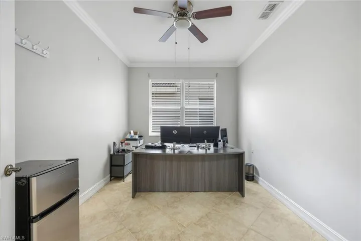 Office space featuring crown molding, ceiling fan, and light tile patterned floors