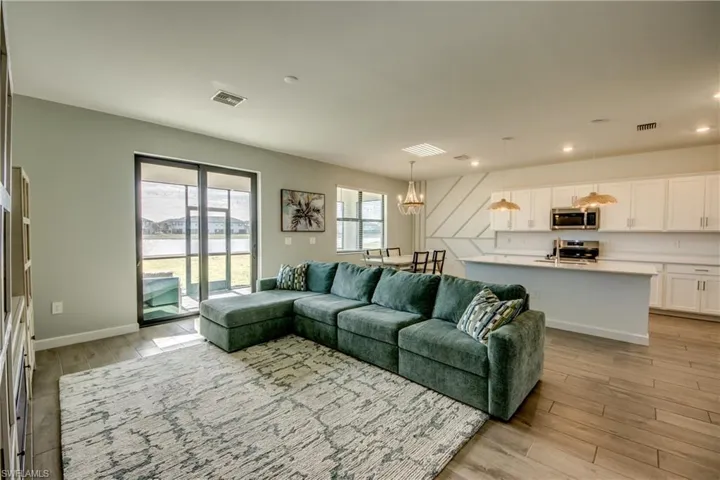 Living room with light wood finished floors, a chandelier, and recessed lighting
