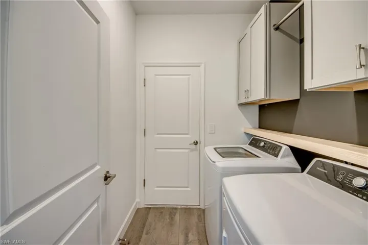 Washroom with light wood finished floors, washer and clothes dryer, and cabinet space
