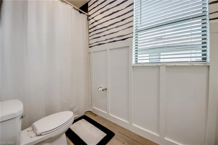 Bathroom featuring curtained shower, a decorative wall, and light wood-style flooring