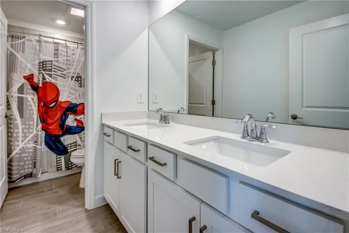 Full bathroom with double vanity, curtained shower, and wood tiled floors