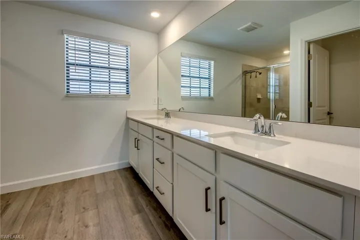 Bathroom featuring double vanity, a shower stall, and light wood-style floors