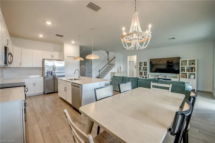 Dining room with stairway, light wood-style floors, a chandelier, and recessed lighting