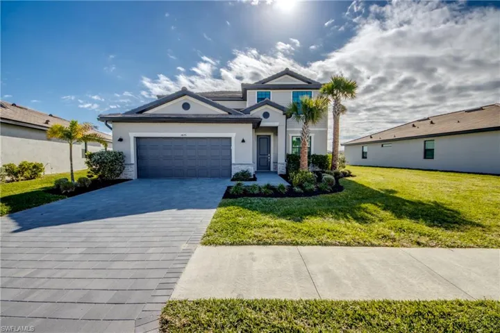 View of front of home with a front yard, an attached garage, decorative driveway, and stucco siding