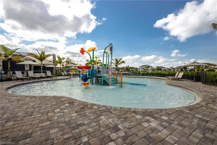 Community jungle gym featuring a water play area, a patio, a community pool, and a residential view