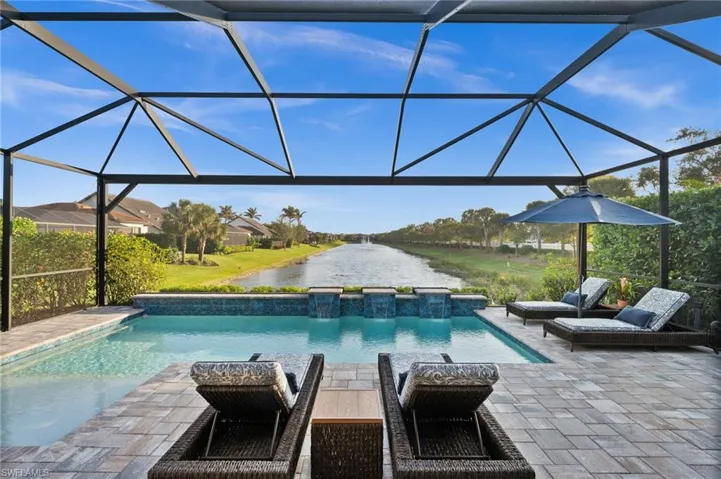 View of pool featuring glass enclosure, a water view, and a patio
