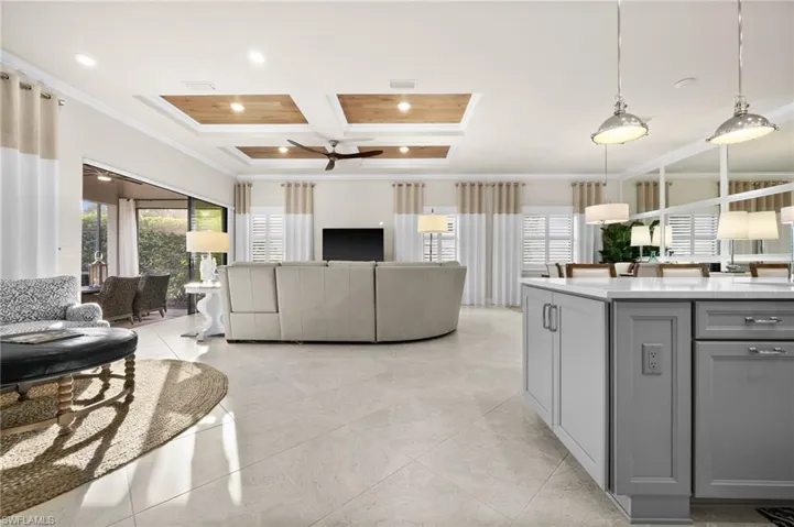 Living room with beam ceiling, ceiling fan, coffered ceiling, and ornamental molding
