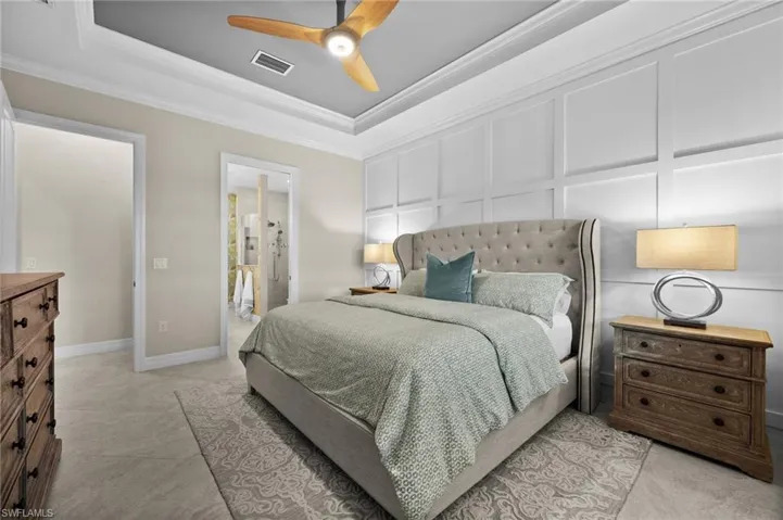 Bedroom with ceiling fan, a raised ceiling, crown molding, and connected bathroom