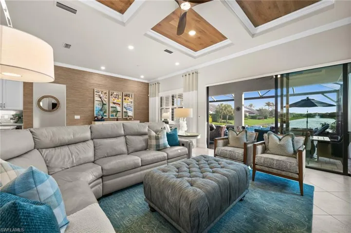 Living room with coffered ceiling, crown molding, ceiling fan, dark tile patterned floors, and beam ceiling