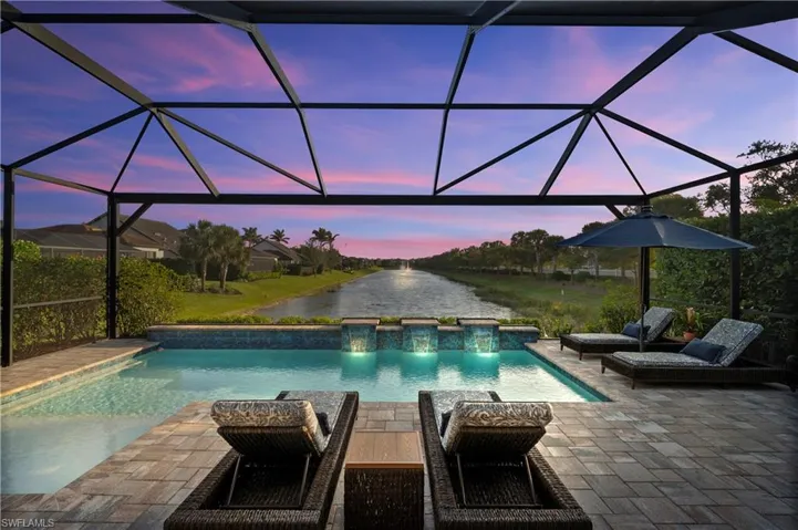 Pool at dusk with a patio, a lanai, and a water view