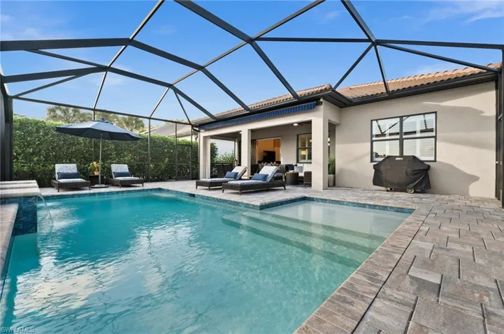 View of swimming pool featuring a patio, pool water feature, glass enclosure, and ceiling fan