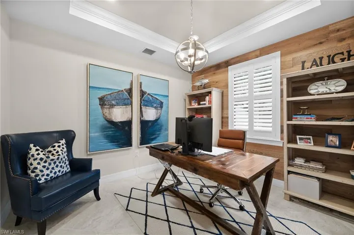 Office with a chandelier, a tray ceiling, ornamental molding, and wood walls