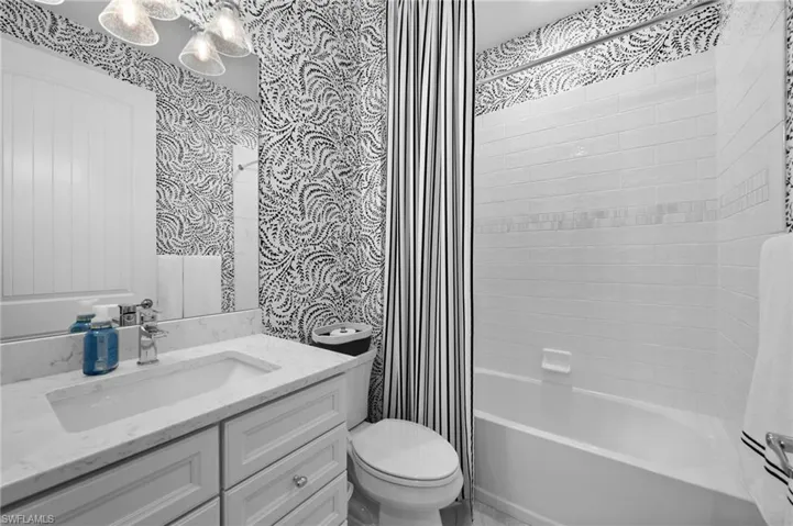 Full bathroom with tiled shower / bath combo, toilet, and vanity