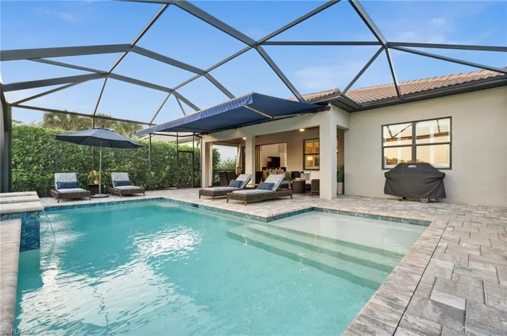 View of swimming pool with glass enclosure, a grill, pool water feature, and a patio