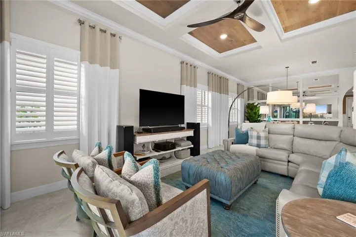 Tiled living room with a healthy amount of sunlight, crown molding, and coffered ceiling