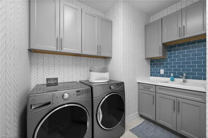 Washroom with sink, light tile patterned flooring, cabinets, and independent washer and dryer