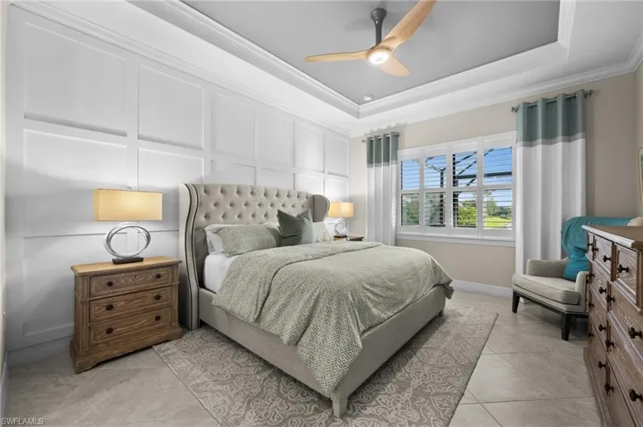 Tiled bedroom with a tray ceiling, ceiling fan, and crown molding