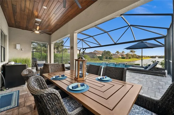 View of patio with ceiling fan, a lanai, and a water view