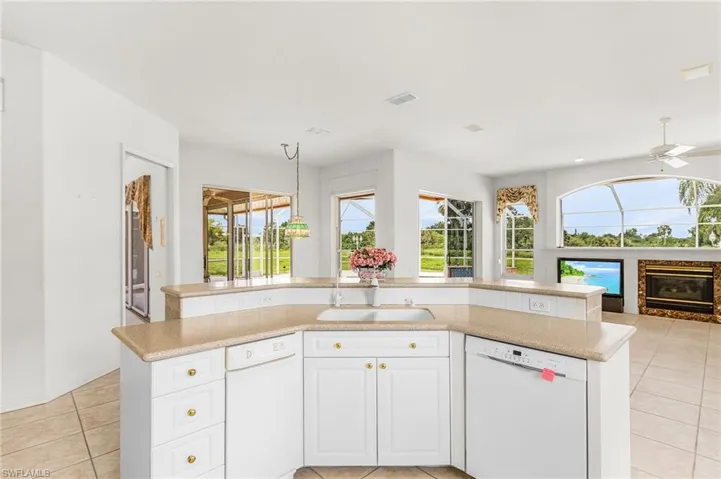 Kitchen featuring dishwasher, light tile patterned floors, open floor plan, light countertops, and a high end fireplace