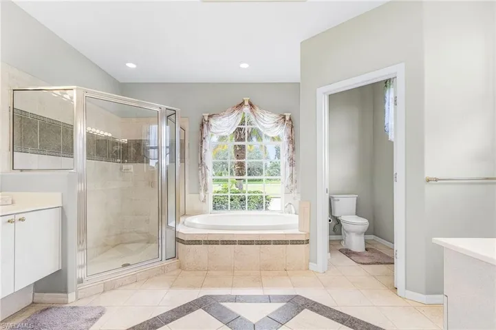 Bathroom with vanity, a bath, tile patterned floors, a shower stall, and inlaid floor details